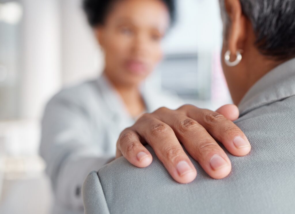 Hand on shoulder, support and women in counselling at work, stress and mental health, closeup with